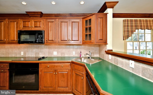 kitchen with decorative backsplash, brown cabinetry, a sink, and black appliances