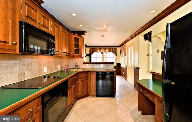 kitchen featuring a notable chandelier, brown cabinetry, a sink, a peninsula, and black appliances