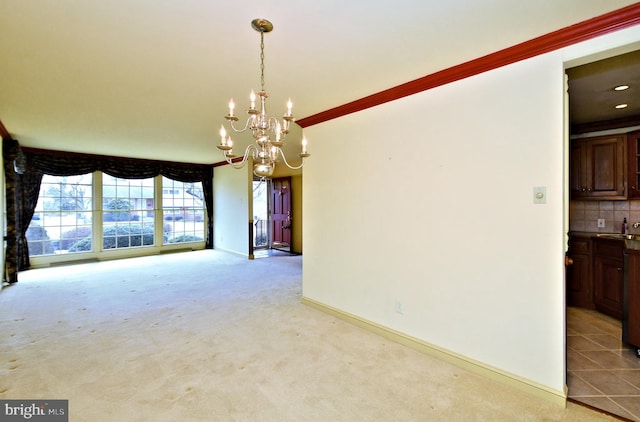 unfurnished room featuring baseboards, light colored carpet, an inviting chandelier, crown molding, and a sink