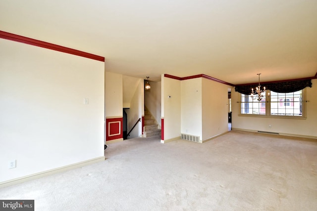 spare room with a notable chandelier, carpet floors, visible vents, stairs, and ornamental molding