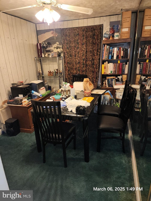 dining room with carpet, wood walls, and ceiling fan