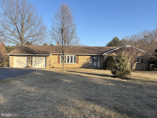 single story home featuring a garage, driveway, a front lawn, and brick siding