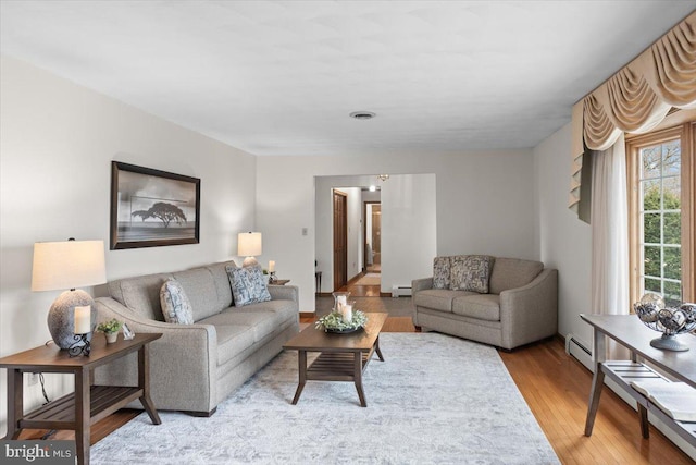 living area with a baseboard radiator, visible vents, a baseboard heating unit, and wood finished floors