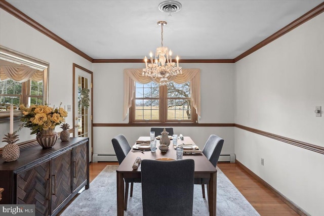 dining space featuring an inviting chandelier, visible vents, baseboard heating, and wood finished floors