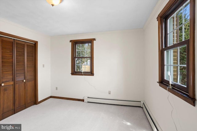 unfurnished bedroom featuring carpet flooring, baseboards, a closet, baseboard heating, and crown molding