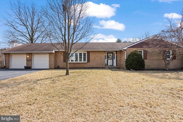 single story home featuring aphalt driveway, brick siding, an attached garage, and a front lawn