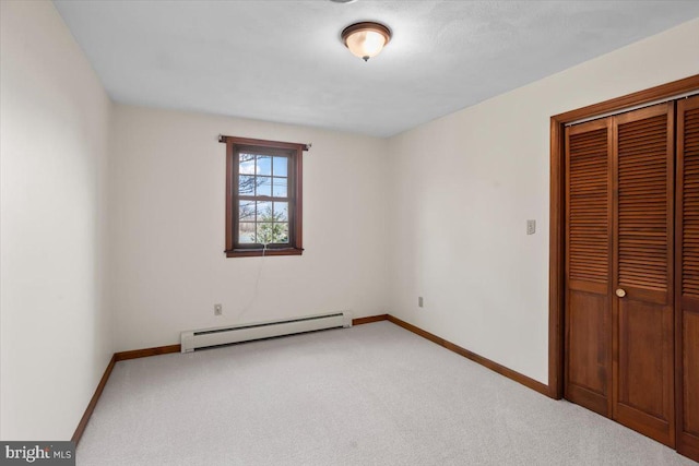 unfurnished bedroom featuring carpet, a baseboard radiator, baseboards, and a closet