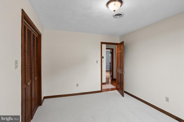 unfurnished bedroom featuring light carpet, baseboards, visible vents, and a closet