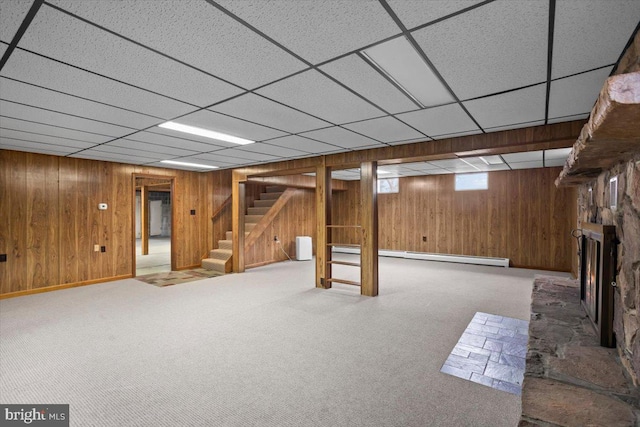 below grade area featuring a fireplace, a baseboard radiator, stairway, carpet flooring, and wooden walls