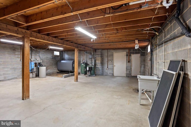 unfinished basement featuring water heater, a sink, and heating fuel