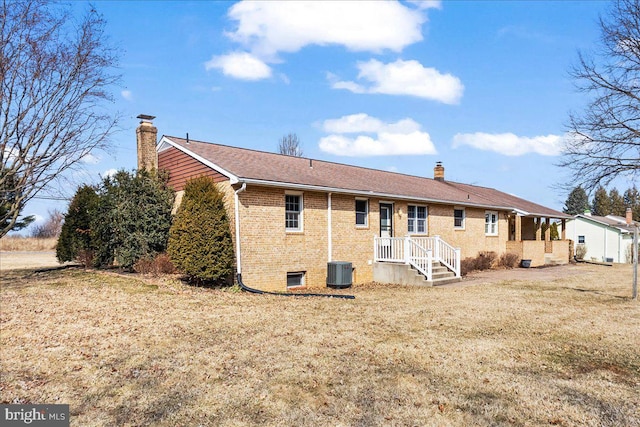 rear view of property featuring a yard, central AC, brick siding, and a chimney