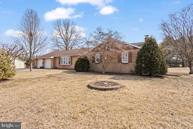 ranch-style home with a garage, a front yard, brick siding, and a chimney