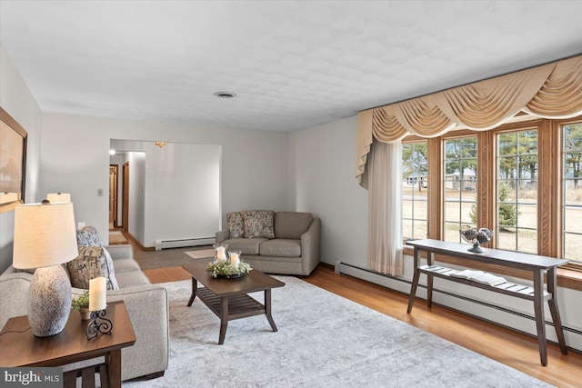 living room featuring baseboard heating, wood finished floors, and visible vents