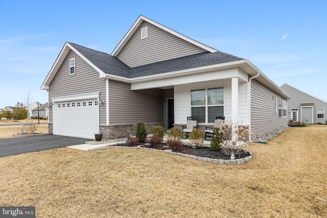 view of front of home with driveway, a shingled roof, a front lawn, and stone siding