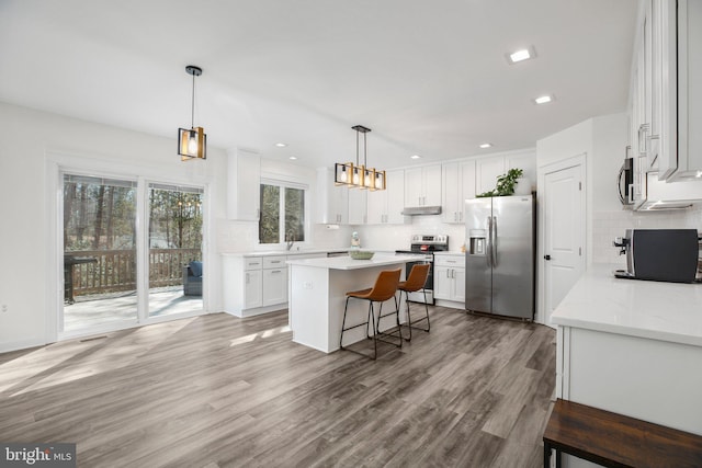 kitchen with white cabinets, light wood-type flooring, stainless steel appliances, and a center island