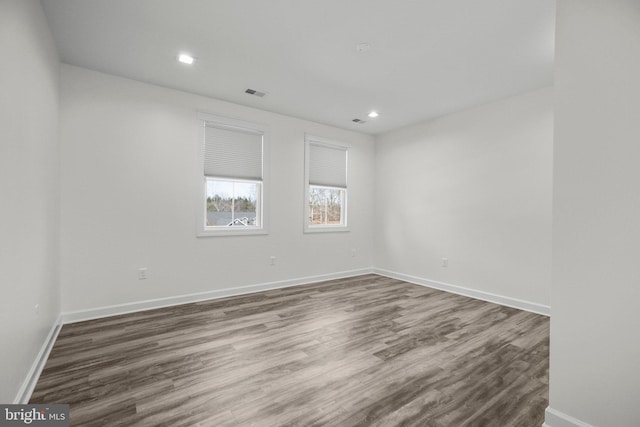 empty room with recessed lighting, visible vents, baseboards, and wood finished floors