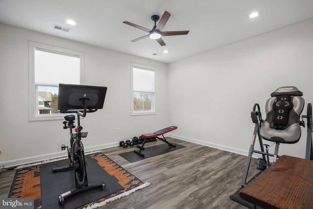 workout room with dark wood-style floors, visible vents, ceiling fan, and baseboards