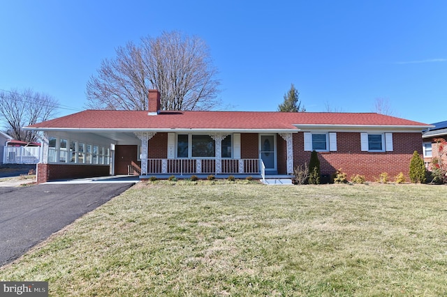 ranch-style house with aphalt driveway, covered porch, brick siding, and a chimney