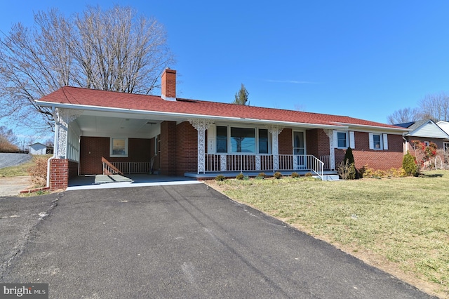 single story home with aphalt driveway, brick siding, a chimney, an attached carport, and a front lawn