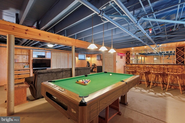 rec room featuring unfinished concrete flooring, a bar, and billiards