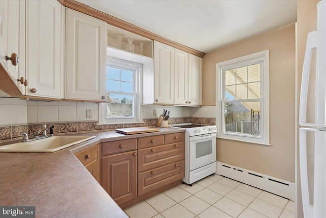 kitchen with a sink, a baseboard heating unit, tasteful backsplash, white appliances, and light tile patterned floors