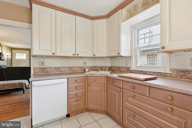 kitchen with backsplash, dishwasher, light tile patterned flooring, white cabinets, and a sink