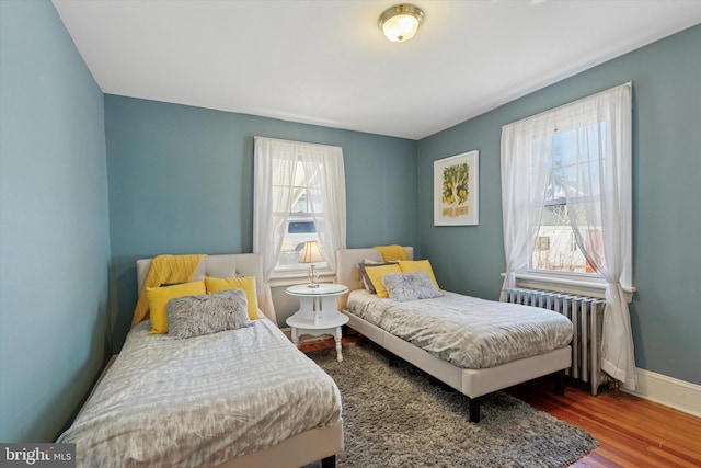 bedroom with radiator heating unit, baseboards, and wood finished floors