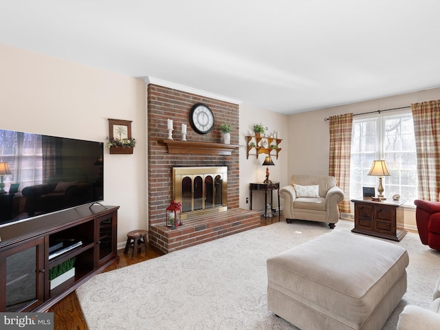 living area featuring a brick fireplace, baseboards, and wood finished floors