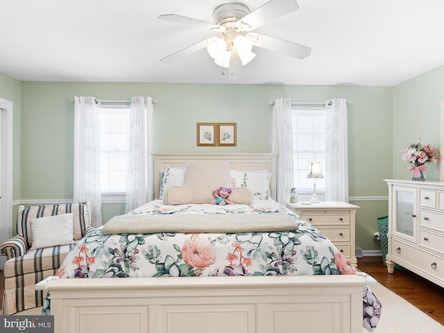 bedroom featuring ceiling fan, dark wood-type flooring, and multiple windows