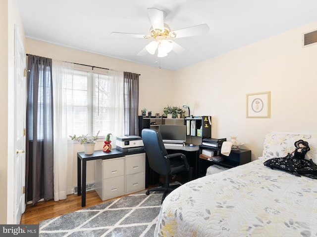 bedroom featuring a ceiling fan, visible vents, and wood finished floors