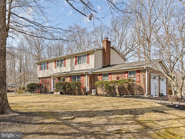 view of front of property with an attached garage, a front yard, a chimney, and brick siding