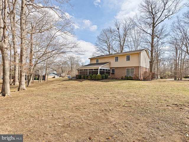 back of house with brick siding, a lawn, and a sunroom