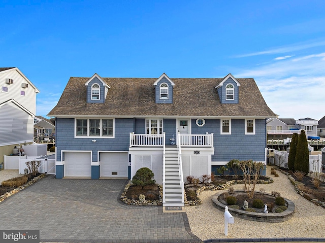 view of front of house with stairway, an attached garage, fence, decorative driveway, and a porch