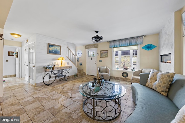 living area featuring stairs, baseboards, and a premium fireplace