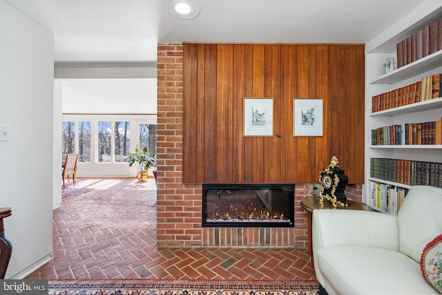 sitting room with brick floor, wood walls, and a fireplace