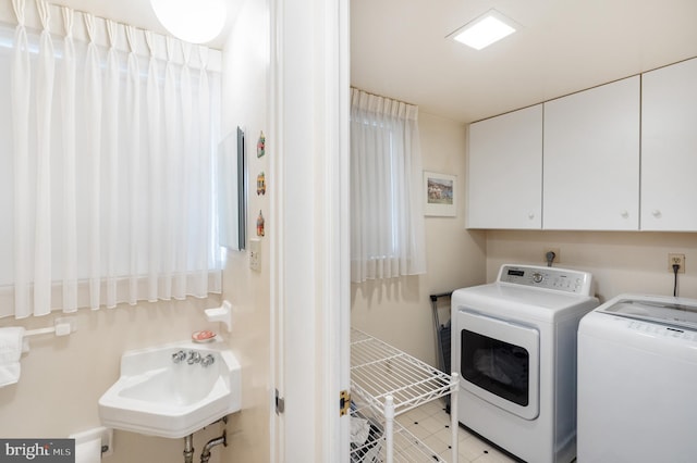 laundry room with cabinet space, a sink, and washing machine and clothes dryer