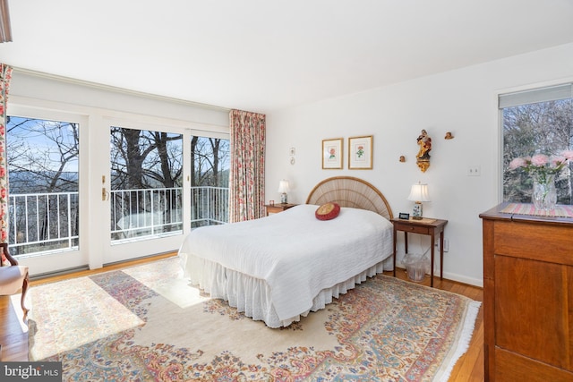 bedroom featuring access to outside, baseboards, and wood finished floors