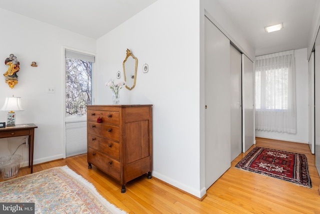 hall with light wood-type flooring and baseboards