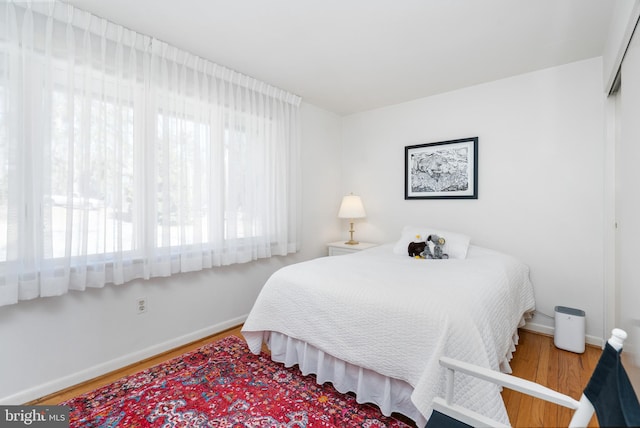 bedroom featuring a closet, wood finished floors, and baseboards