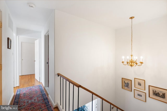 corridor featuring light wood-style flooring and a notable chandelier