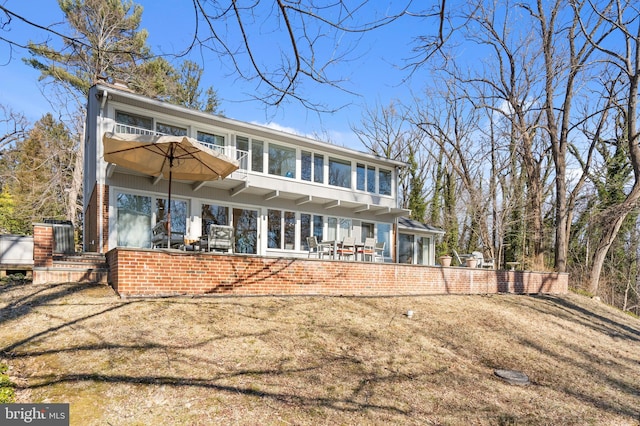 back of house featuring brick siding, a patio, and a balcony