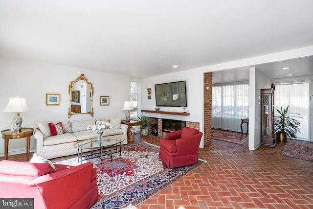 living area featuring a brick fireplace, brick floor, and recessed lighting