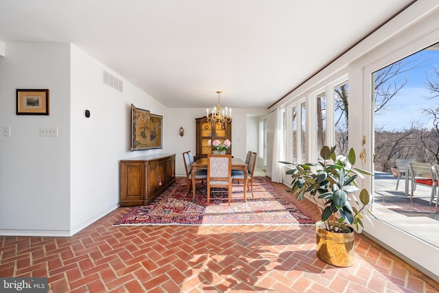 dining area featuring a chandelier, brick floor, visible vents, and baseboards