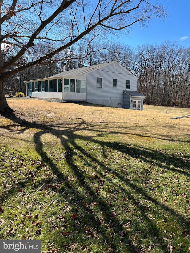 back of property with a sunroom, a yard, and a chimney