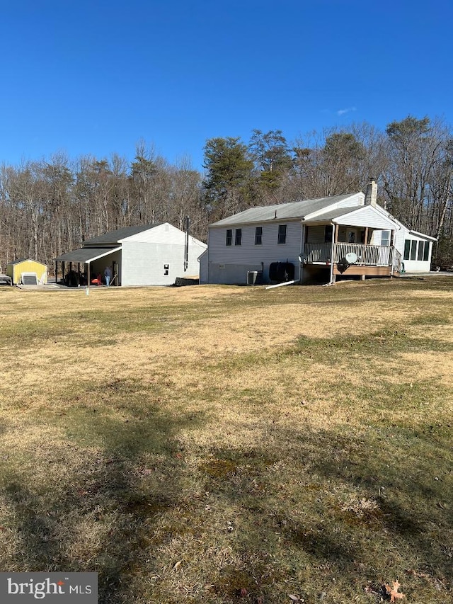 back of house featuring a yard, a carport, and a wooden deck