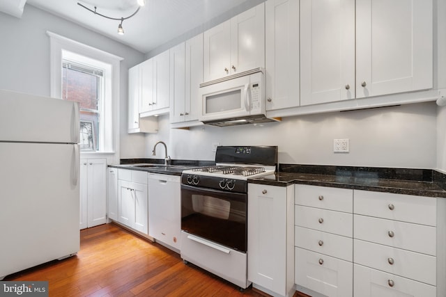 kitchen featuring white appliances, white cabinetry, and a sink