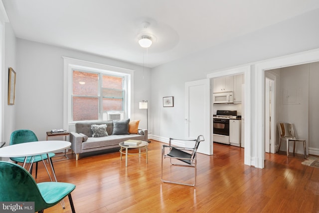 living area with light wood finished floors, cooling unit, and baseboards