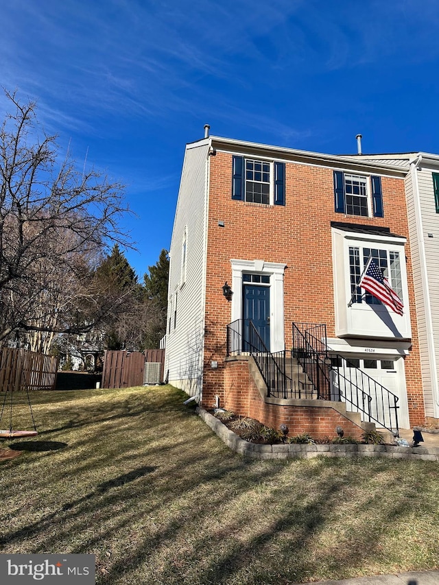 view of front of home featuring entry steps, brick siding, a front yard, and fence