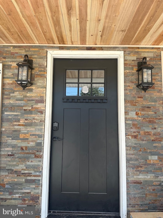 view of exterior entry featuring a porch and brick siding