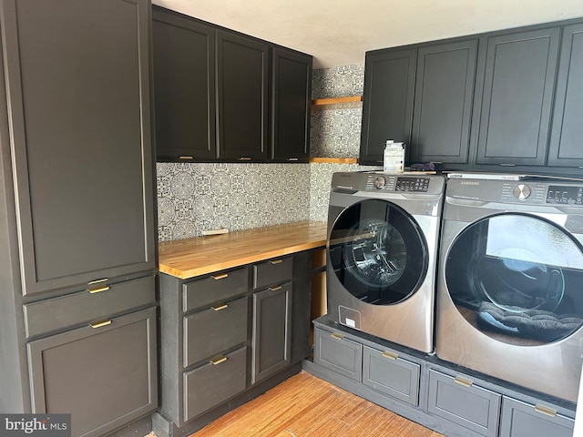 washroom with washing machine and clothes dryer, cabinet space, and light wood-style floors